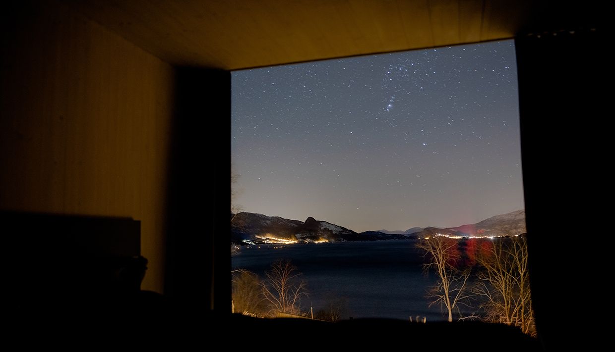 Panoramic view of the fjord and stars from inside the cabin near Hardangerfjord.