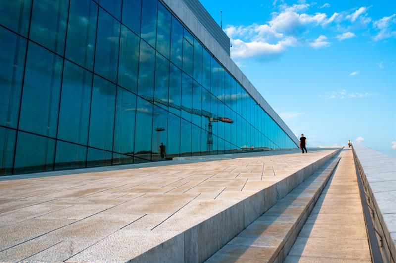 Eksteriørbilde av operaen med de store glassvinduene på den ene siden.