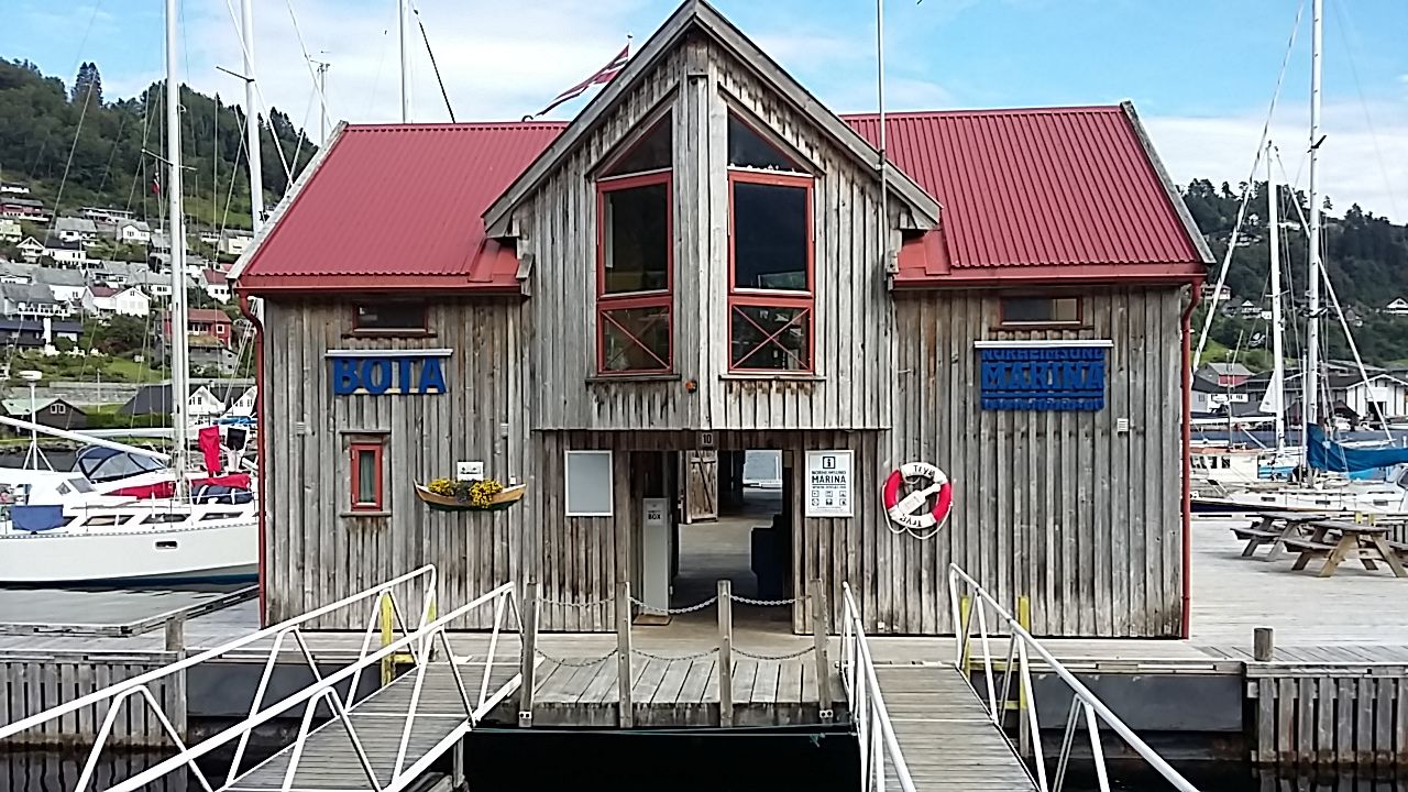 Inngangen til Norheimsund Marina med skilt, treverk og gjestehamn i bakgrunnen.