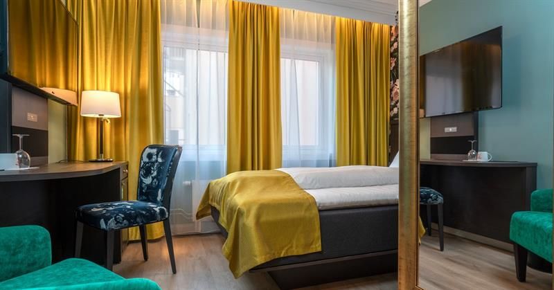 Soverom Thon Hotel Høyers. Gule gardiner, grønn stol, skrivebord, seng med gult teppe.