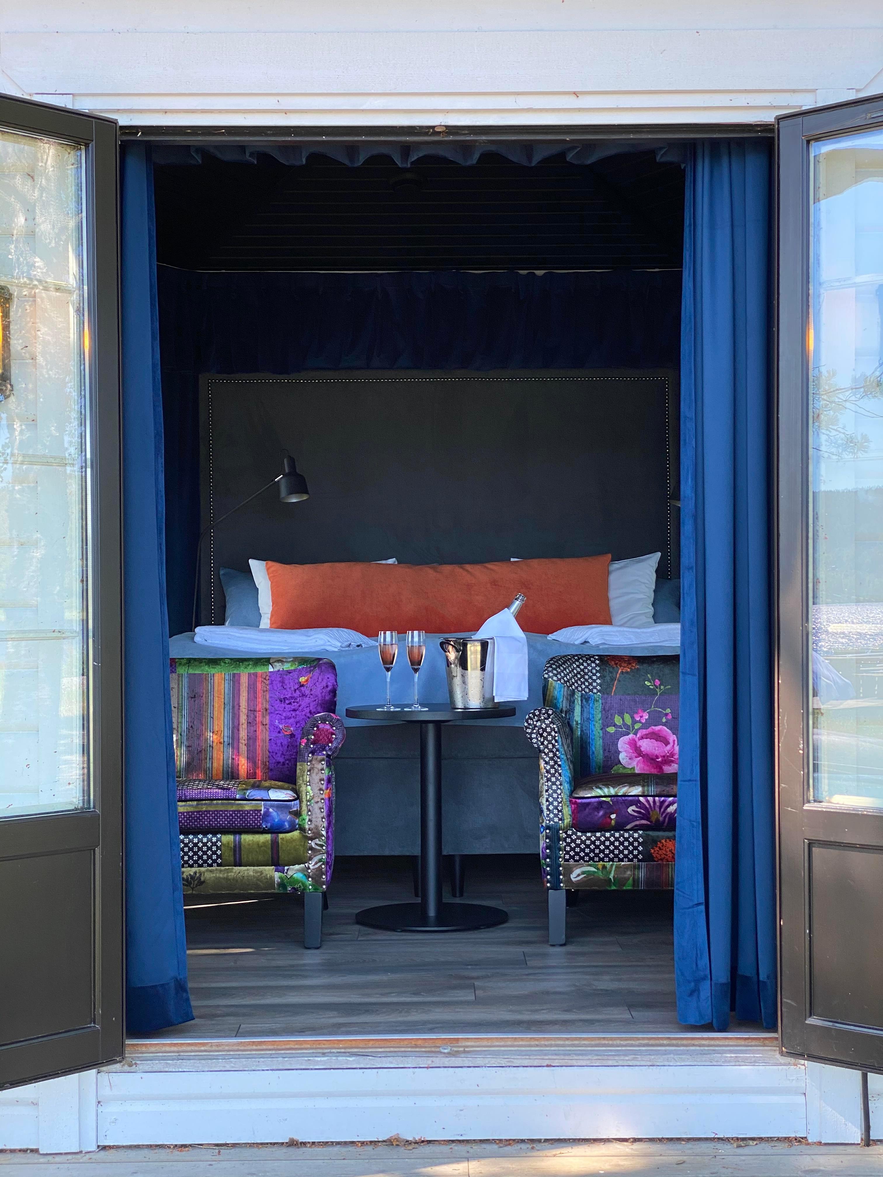 2 chairs with flowery cover, 2 glasses with champagne in a room seen from outside