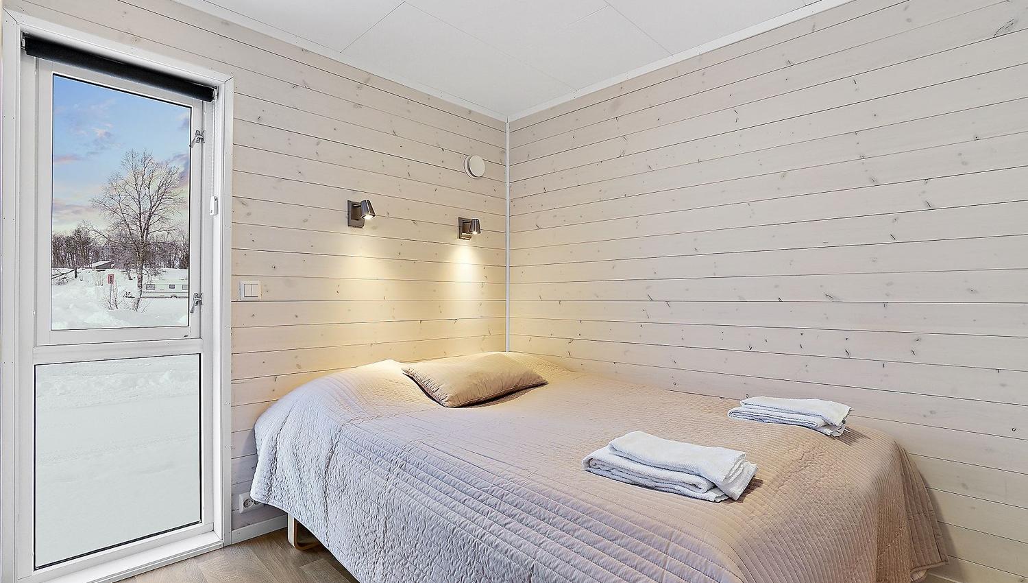 Bedroom with double bed, wooden walls, and view of snowy landscape