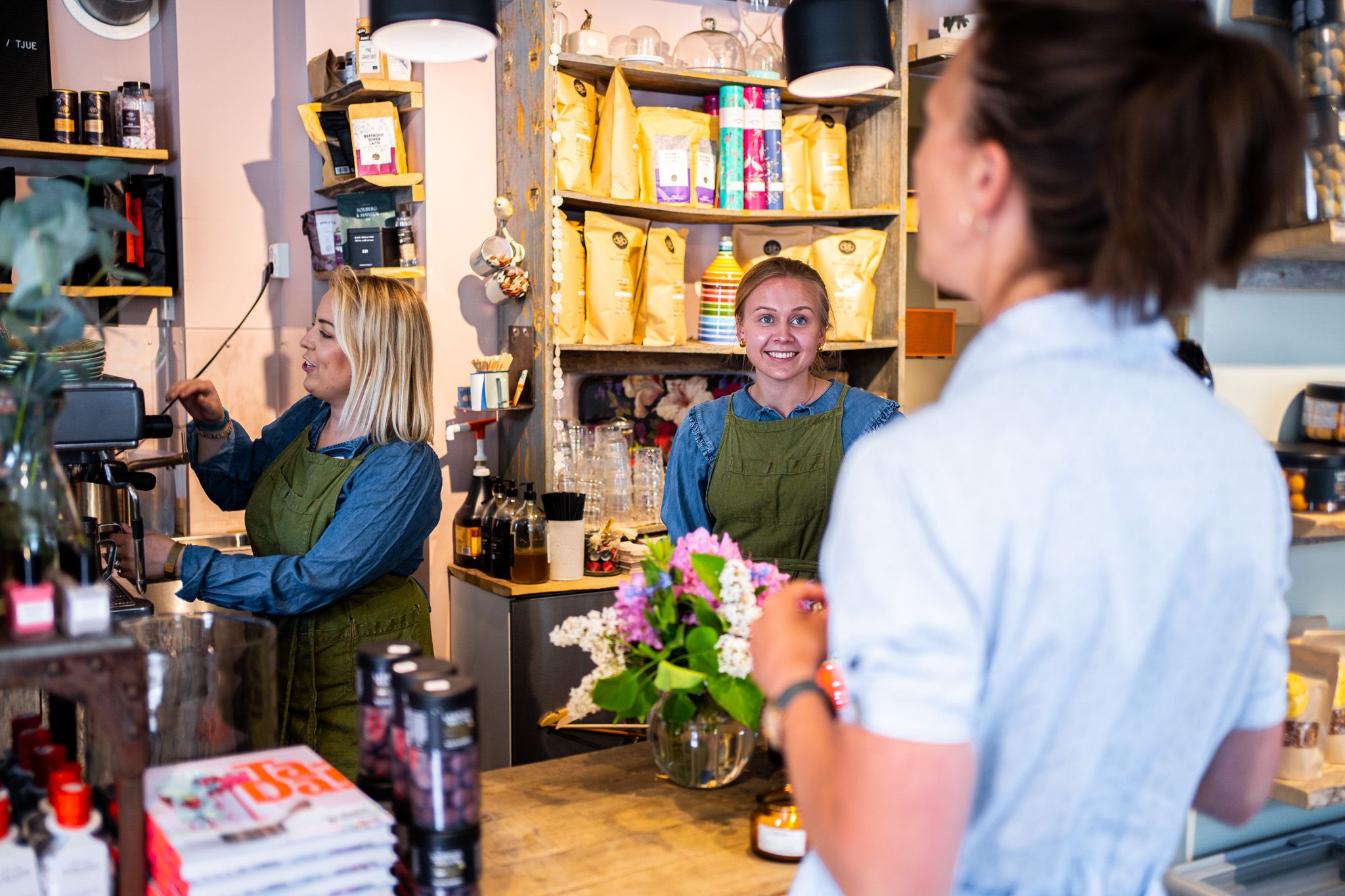 to damer som jobber i en butikk, som snakker med en kunde