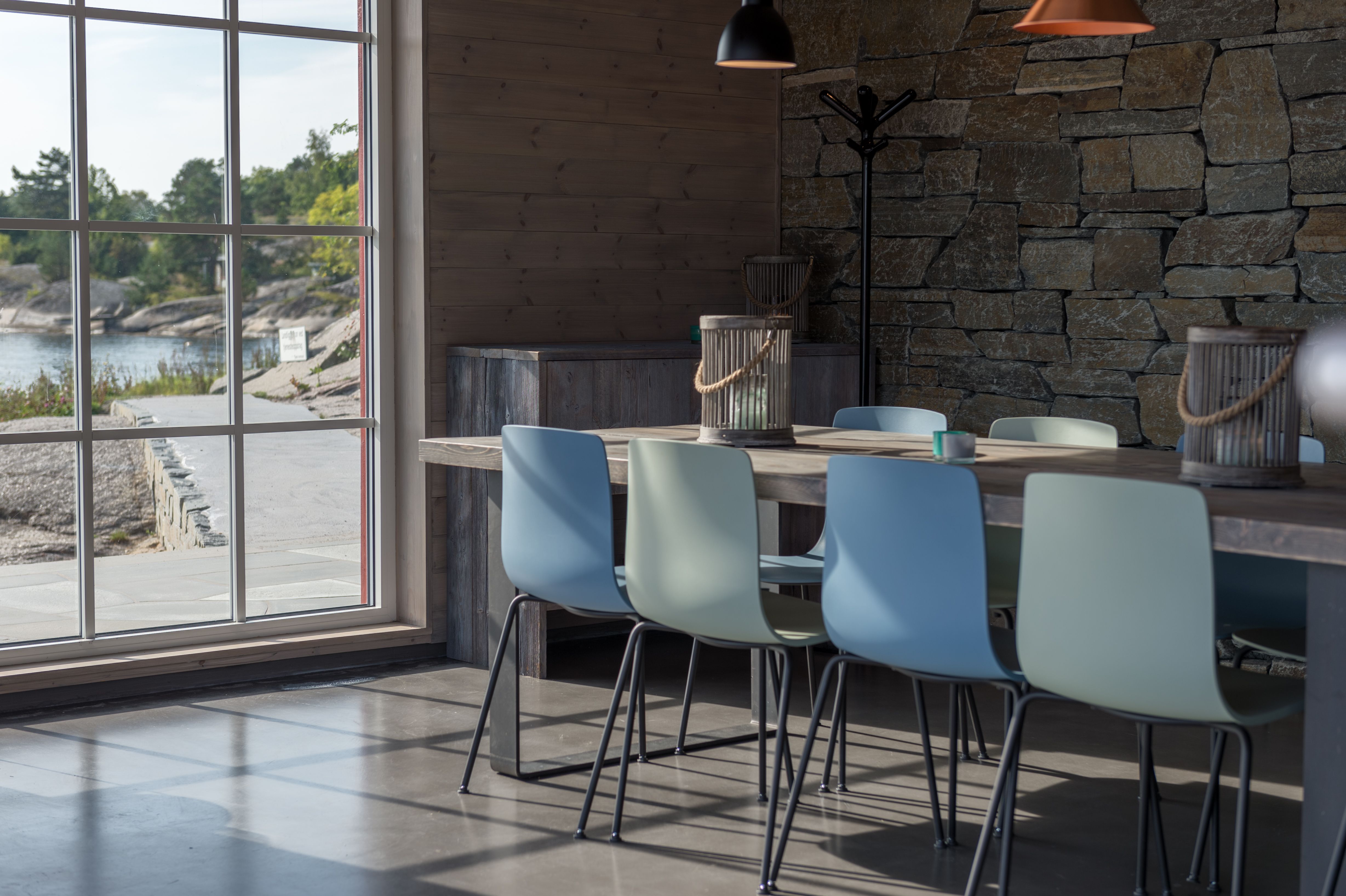 Blue and green chairs at a long table by the window