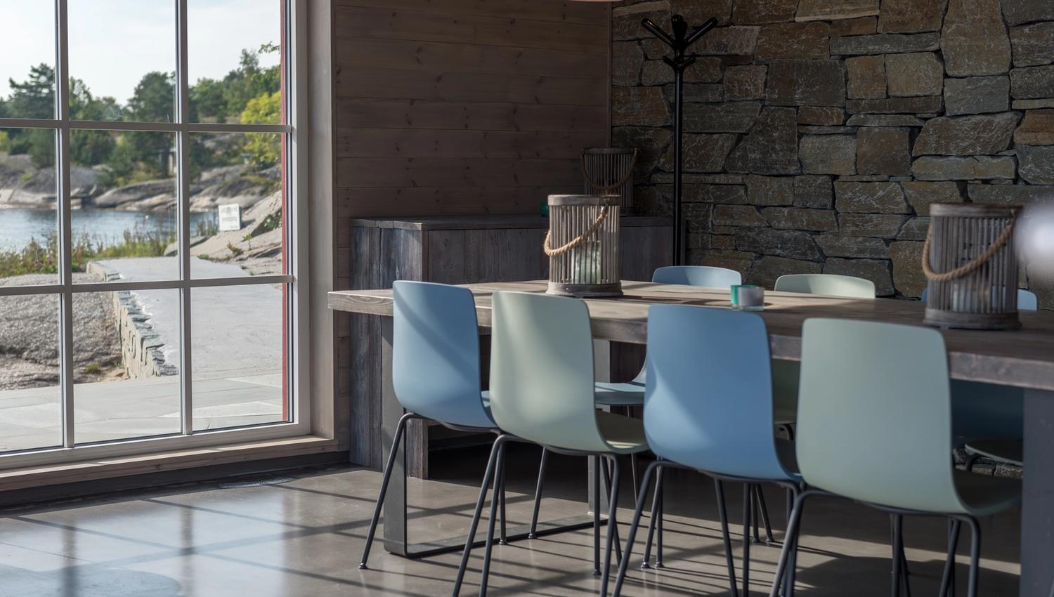 Blå og grønne stoler ved langbord ved vindu