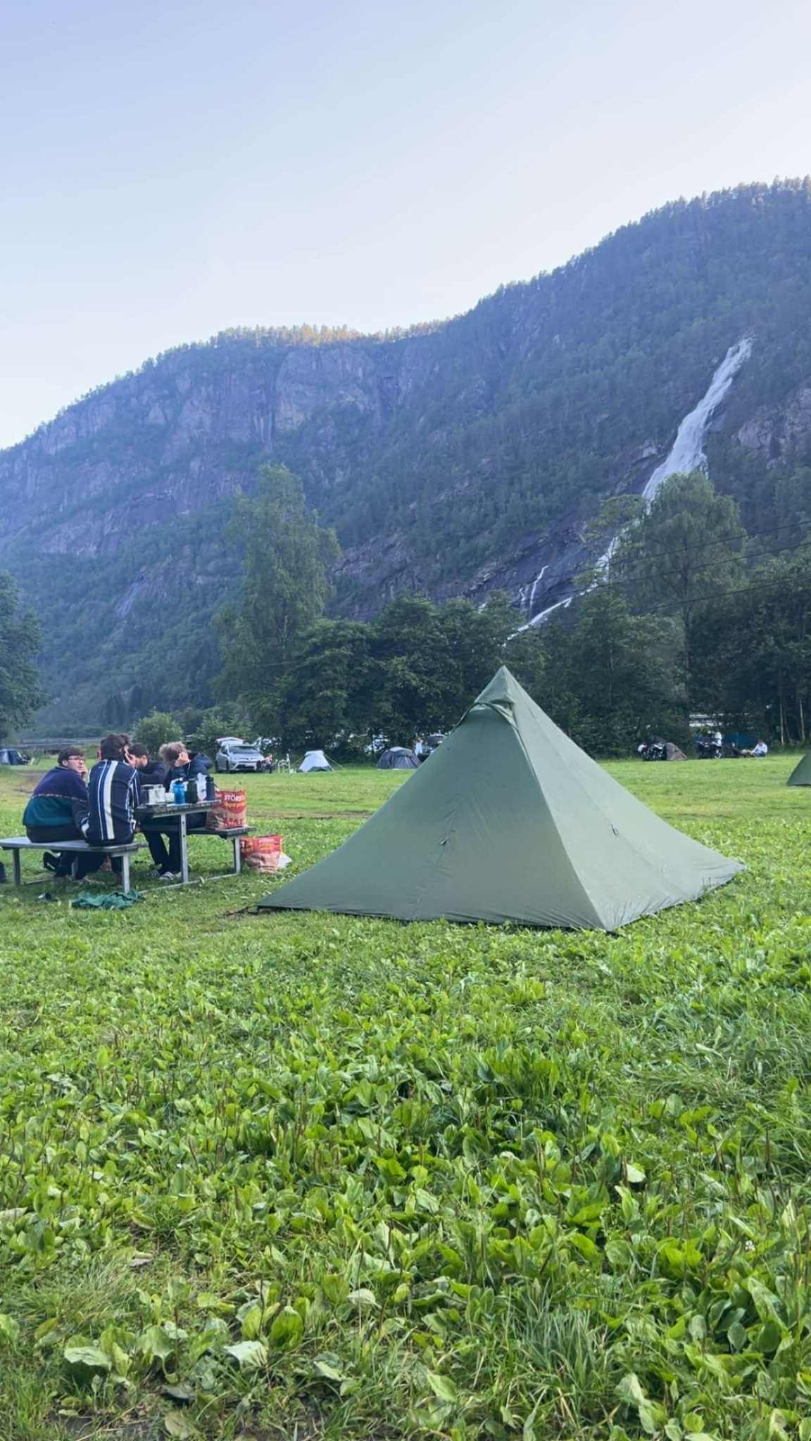 Familiecamping ved Hildal Camping omgitt av grøne fjell og fossande vatn.