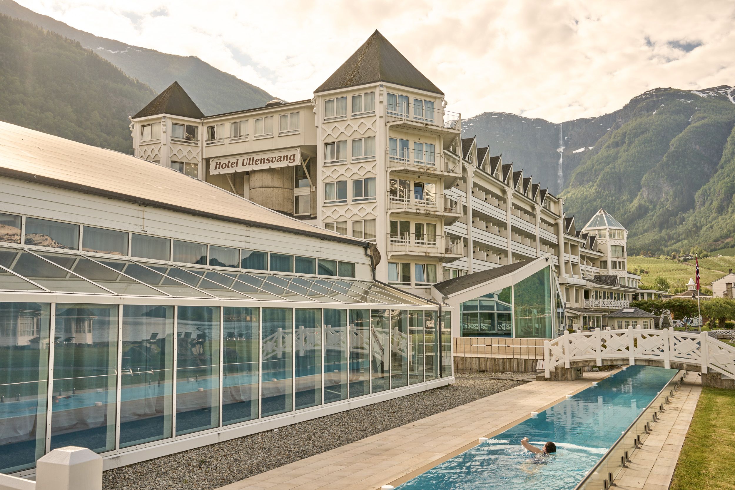 Gjesten nyt det langstrekte utandørsbassenget med utsikt til Hardangervidda og fjella bak Hotel Ullensvang.