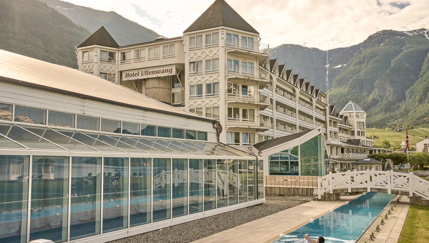 Gjesten nyt det langstrekte utandørsbassenget med utsikt til Hardangervidda og fjella bak Hotel Ullensvang.