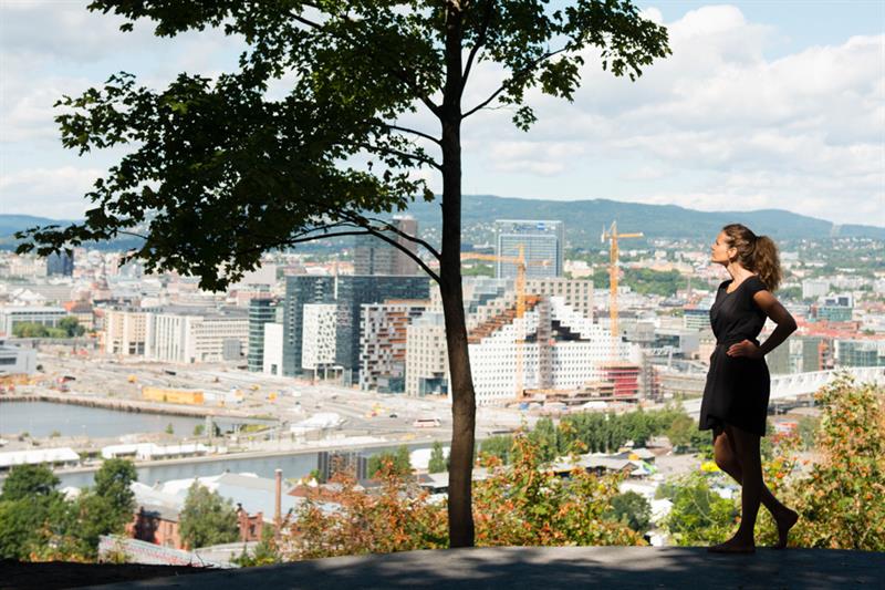 A girl under a tree in front of a view of the city.