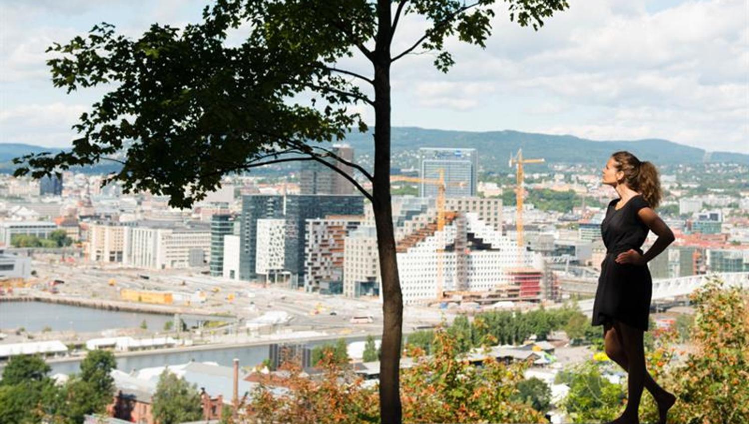A girl under a tree in front of a view of the city.