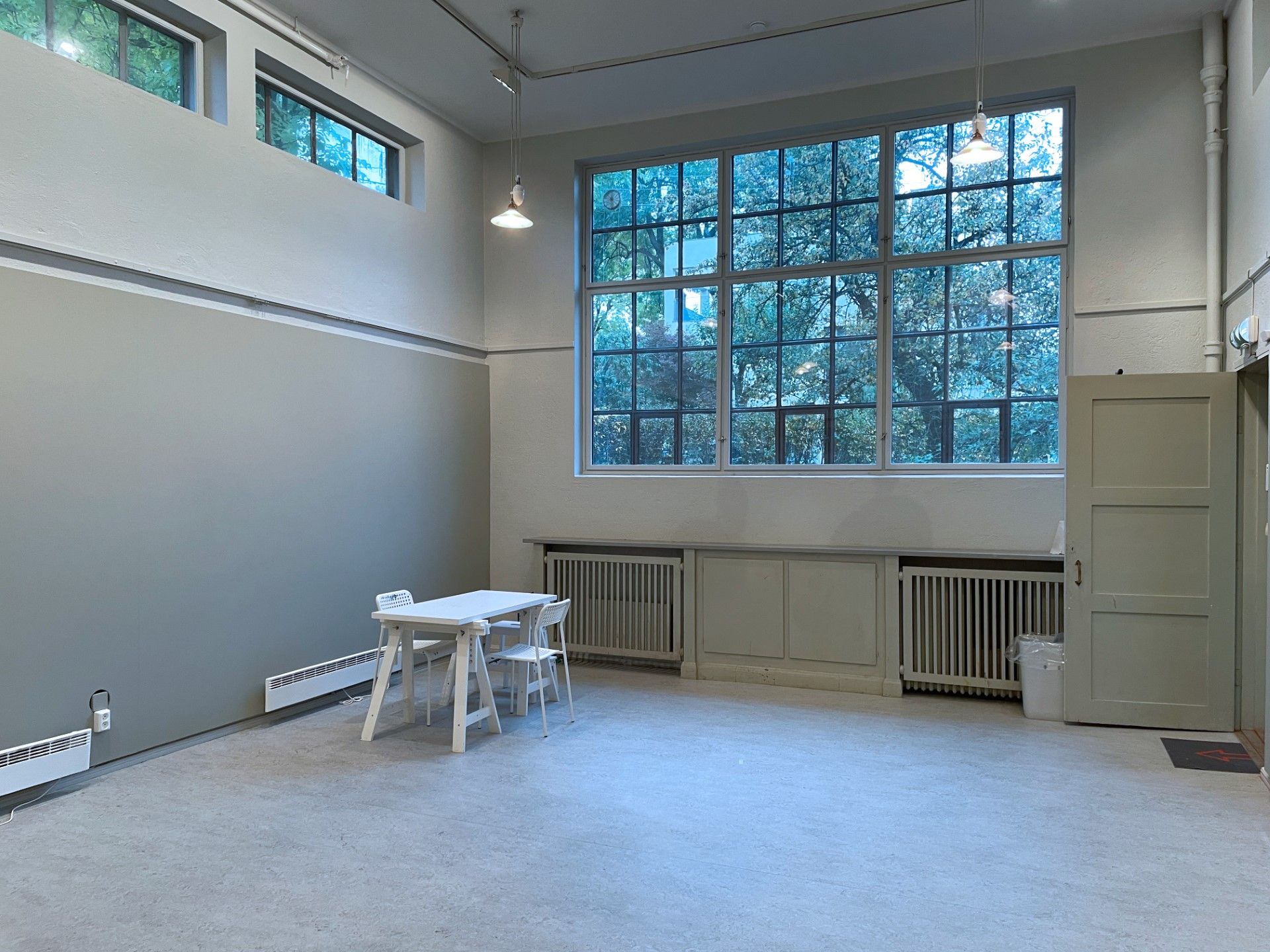 Room with a high ceiling and a large window facing the garden