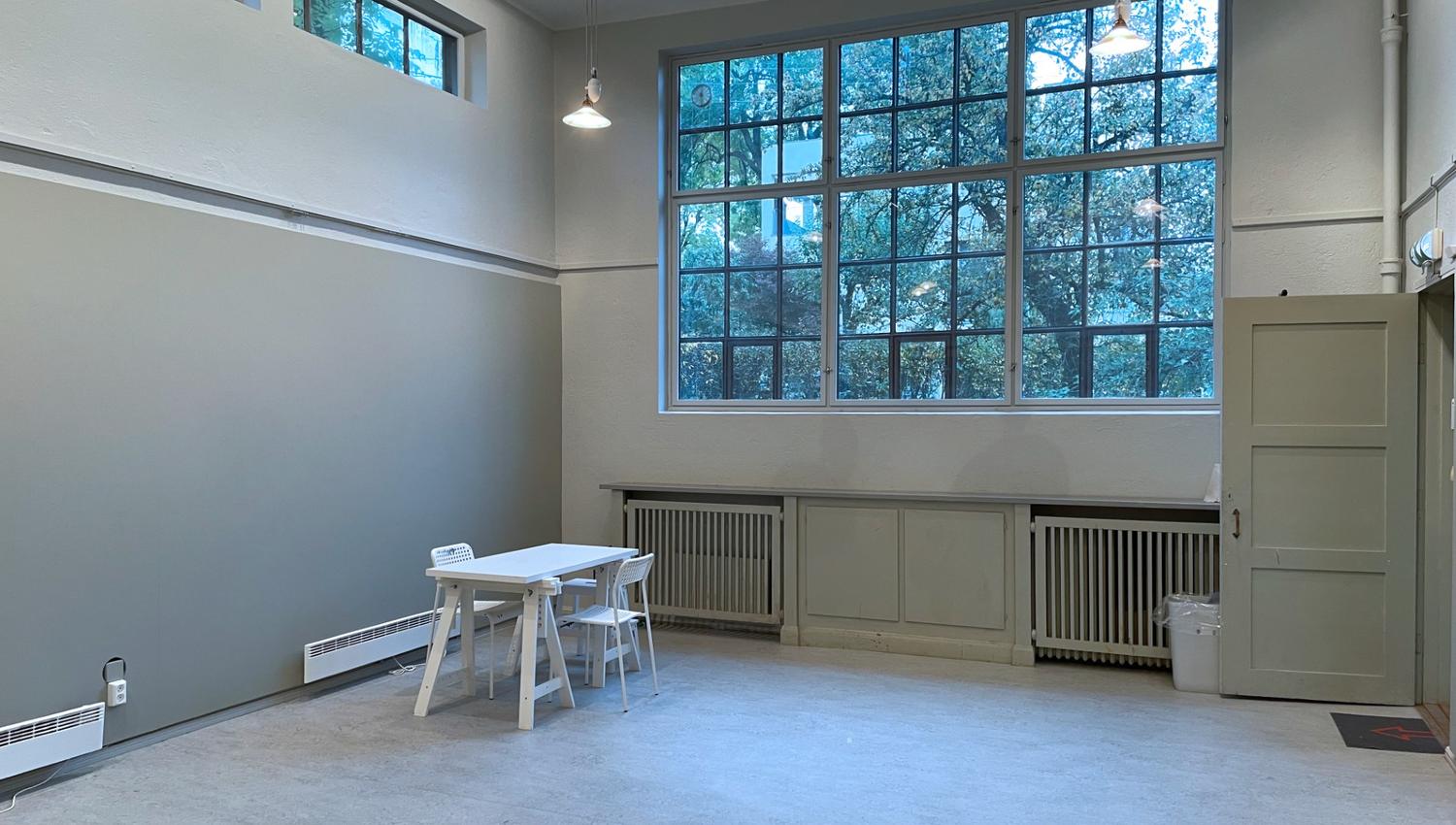 Room with a high ceiling and a large window facing the garden