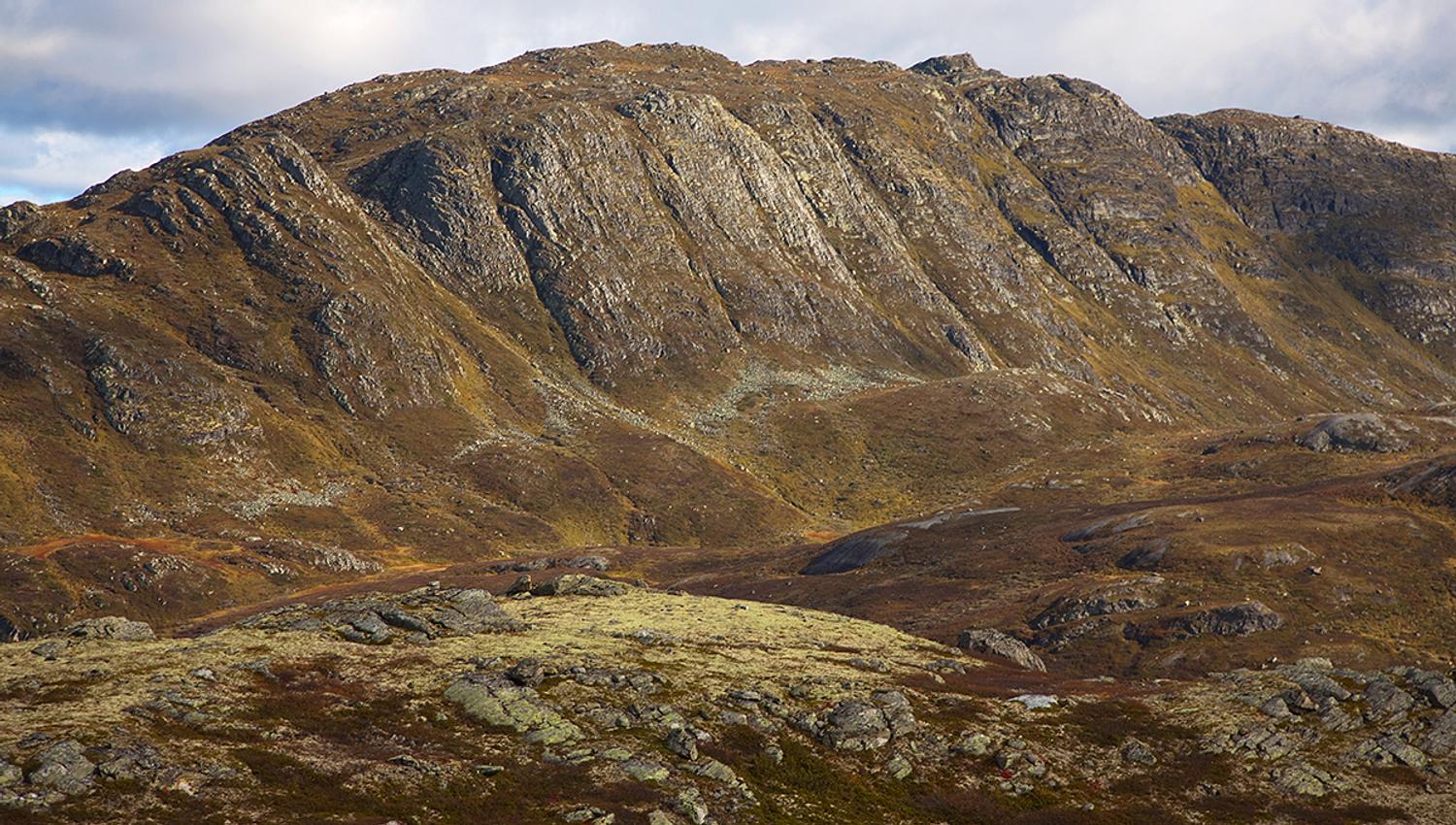 The summit point of Horntinden is located on a long mountain ridge, showing its steep flank to the photographer, while the trail leads up on the less