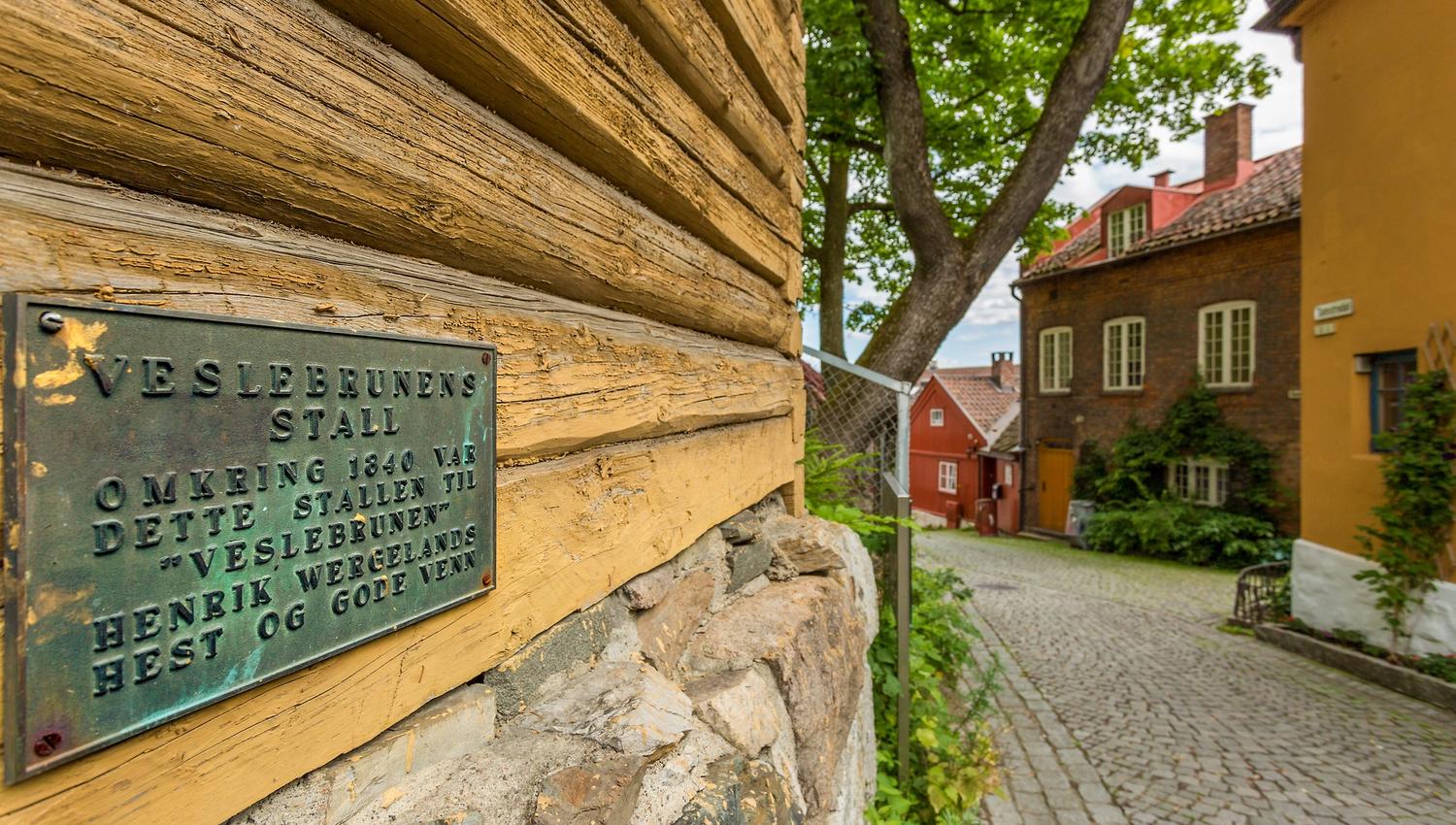 Plakett på et gammelt, gult trehus.