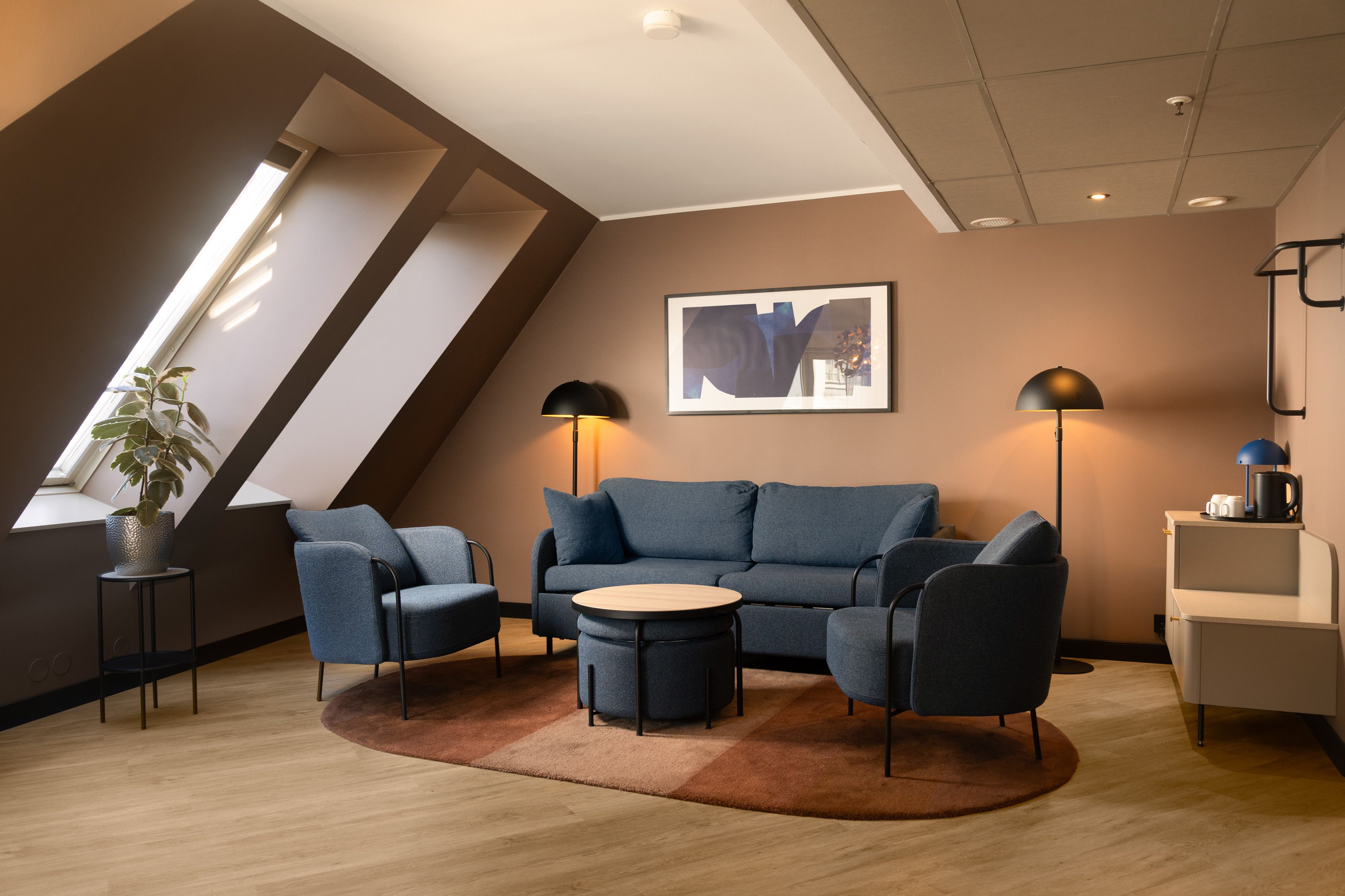 Hotel room with blue sofa, blue armchairs, beige walls and large windows