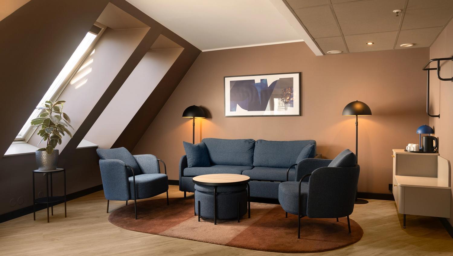 Hotel room with blue sofa, blue armchairs, beige walls and large windows