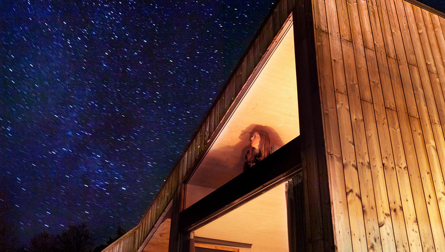 Guest looking up at the starry sky from inside the cabin near Hardangerfjord.