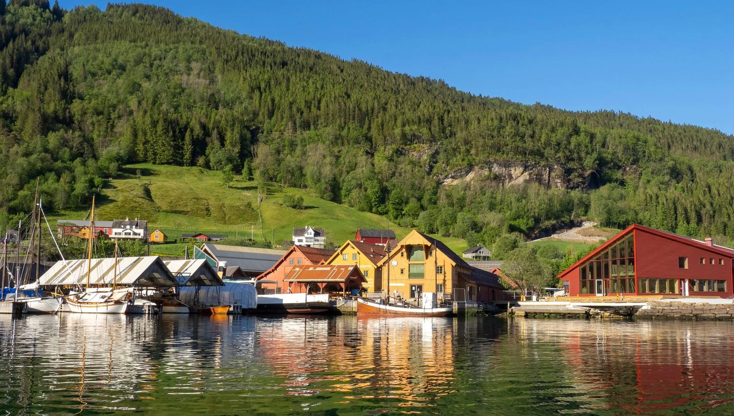 Overview of the Hardanger Maritime Center with the new visitor building, boats and workshops by the dock.