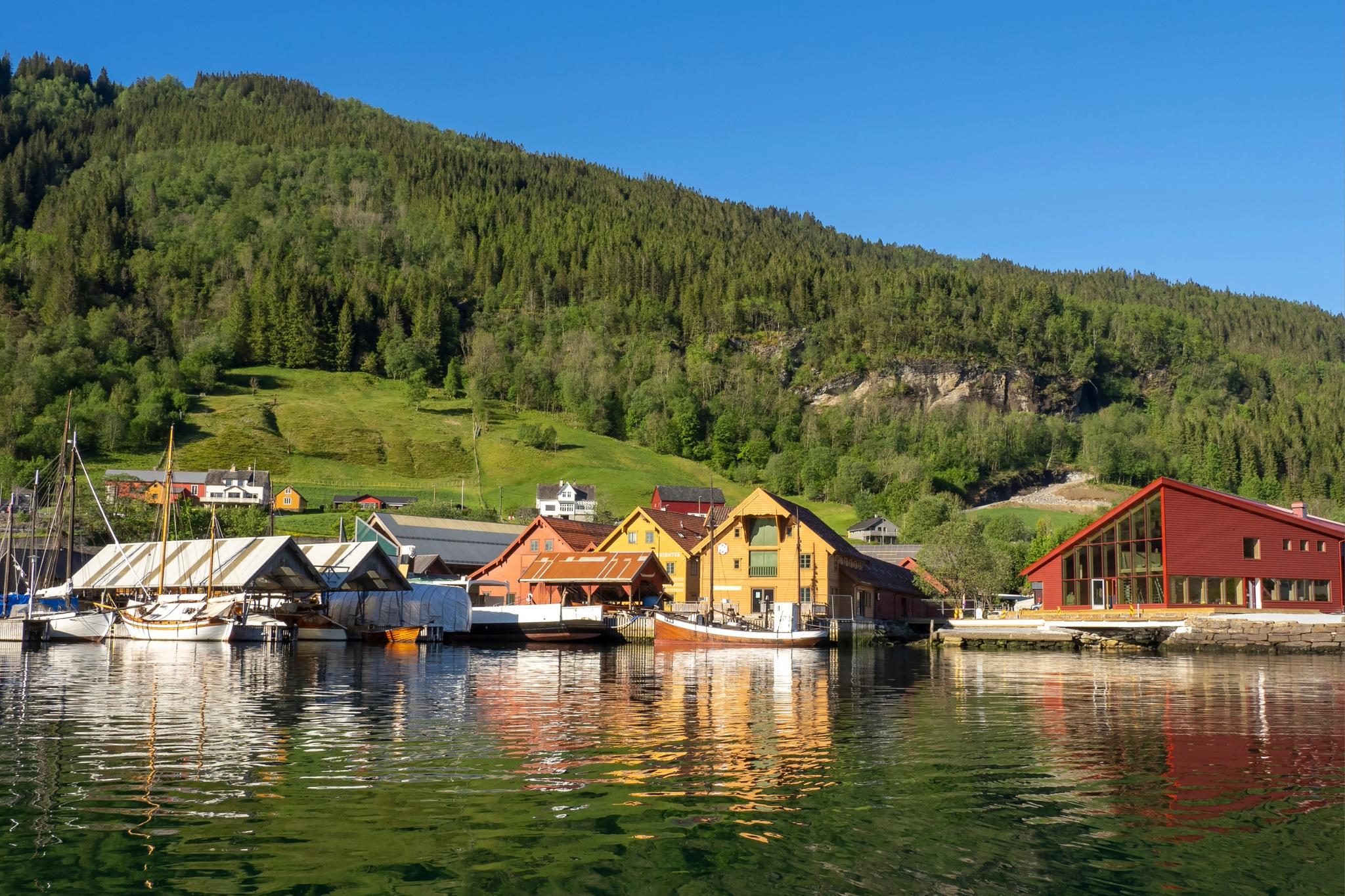 Overview of the Hardanger Maritime Center with the new visitor building, boats and workshops by the dock.