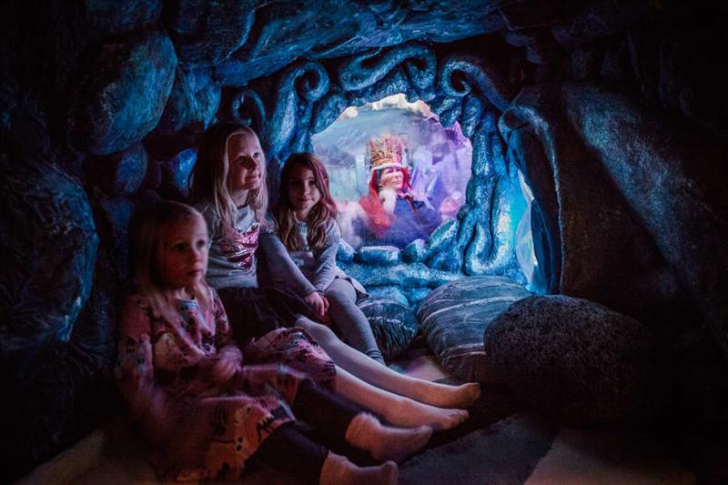 Tre barn som sitter i en hule