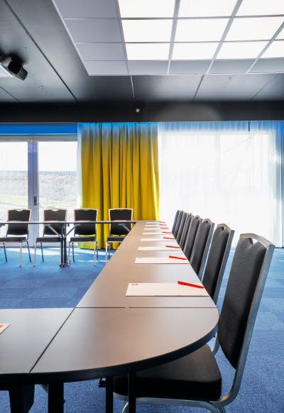 Interiør av konferanserom med stoler, bord og store panoramavinduer.
