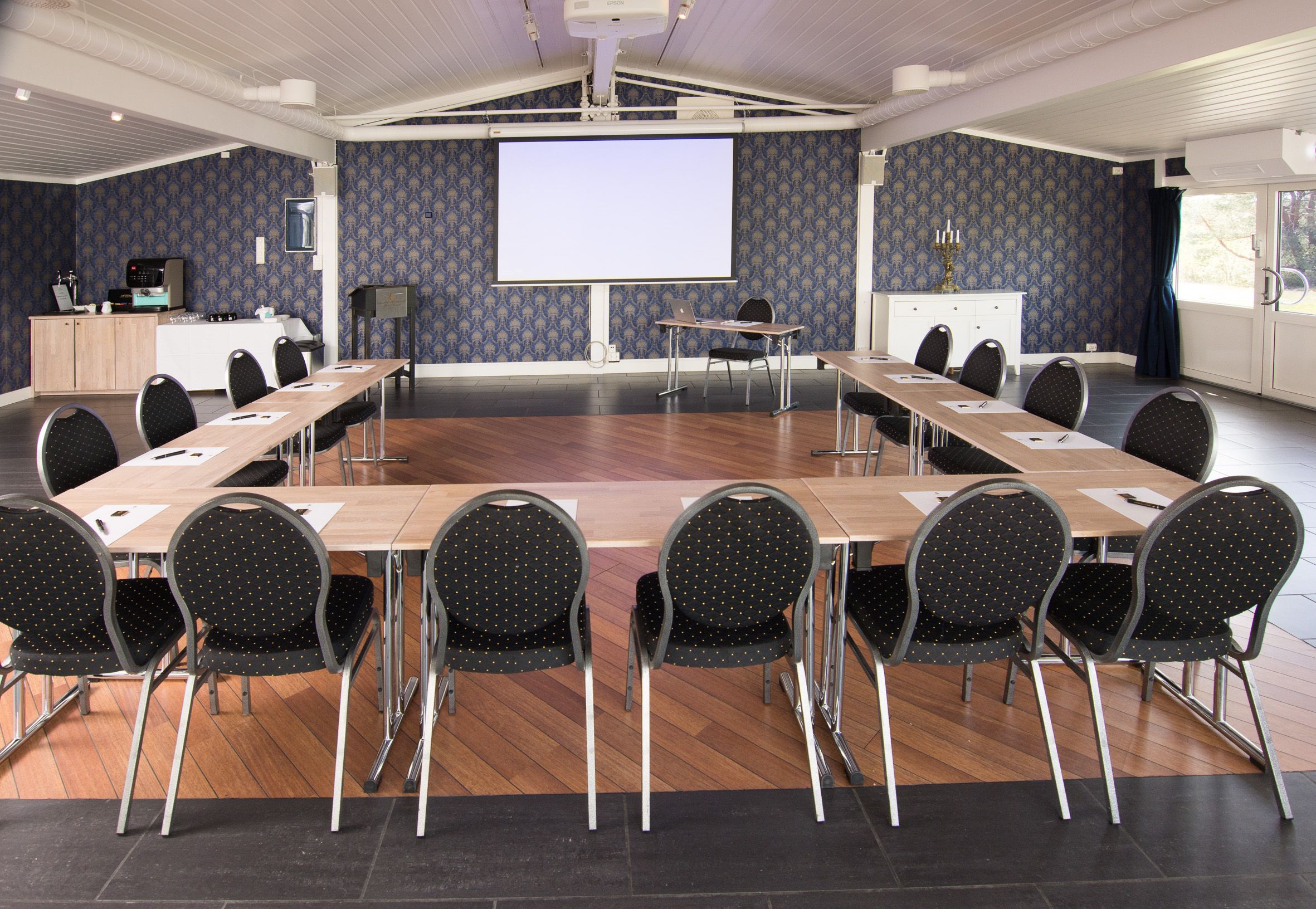 konferanserom med bord og stoler i u-formasjon.