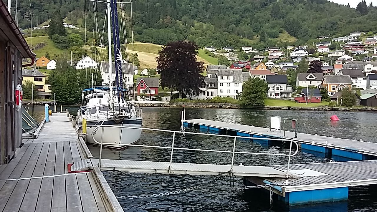 Bryggeanlegg og båtplassar ved Norheimsund Gjestehamn, med utsikt mot sentrum og fjellsider.