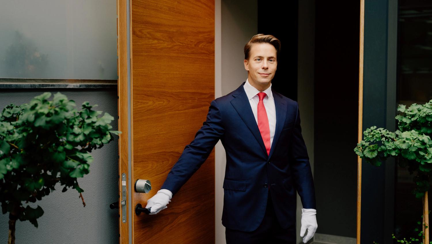 Male butler holding the door open