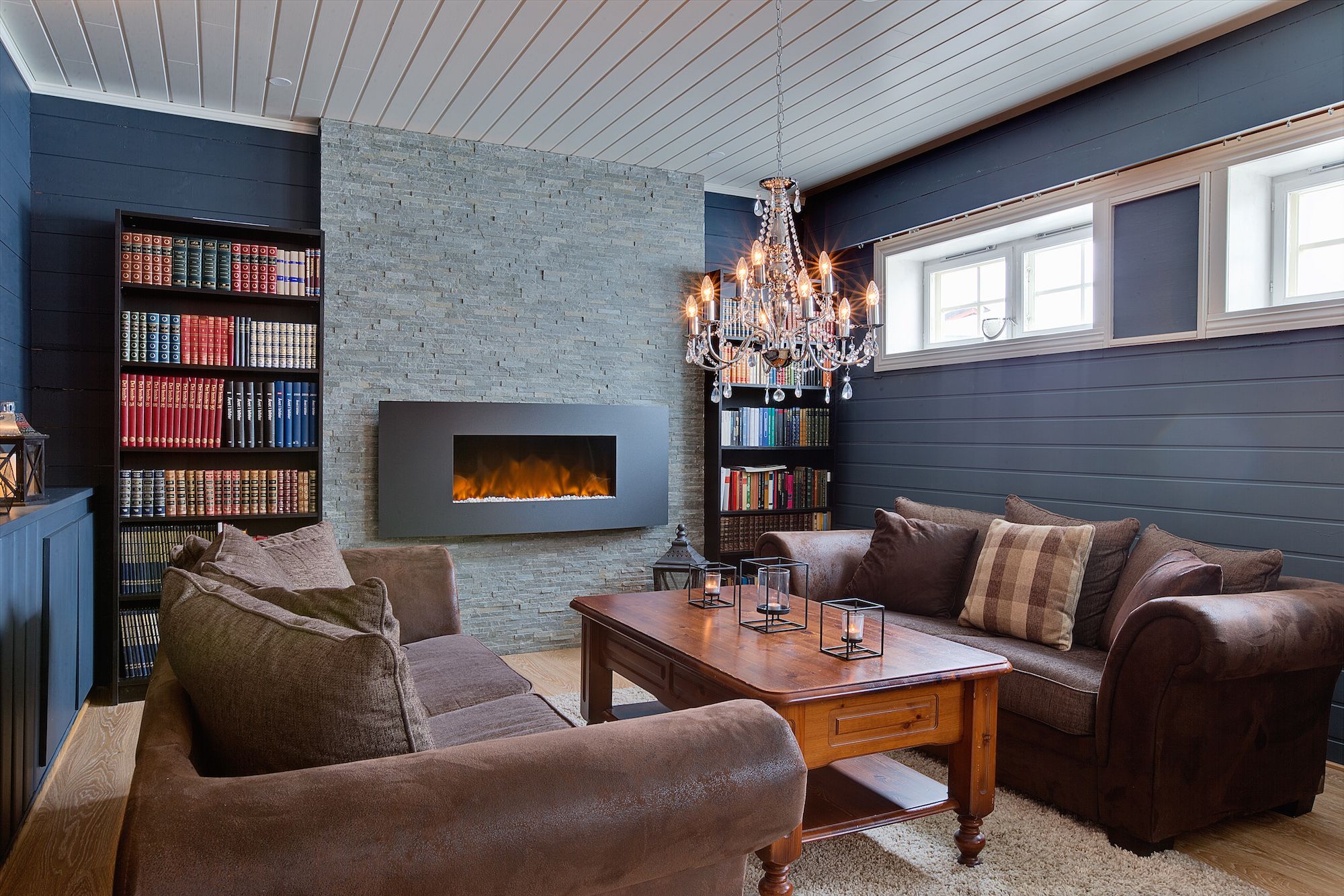 One of the saloons of a mountain lodge with leather sofas and a fireplace built into the wall