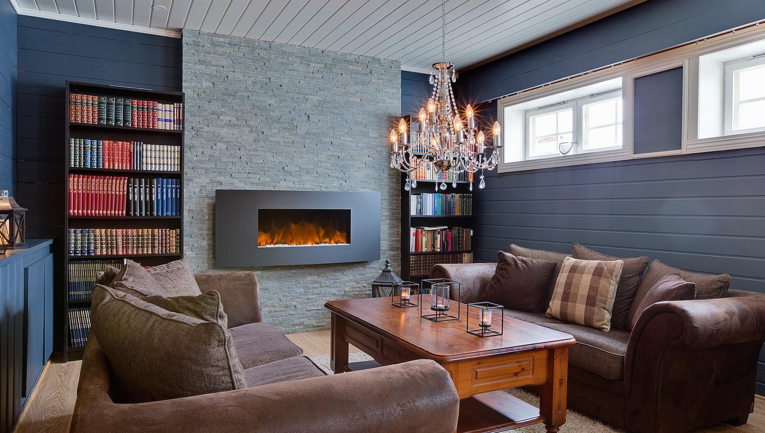 One of the saloons of a mountain lodge with leather sofas and a fireplace built into the wall