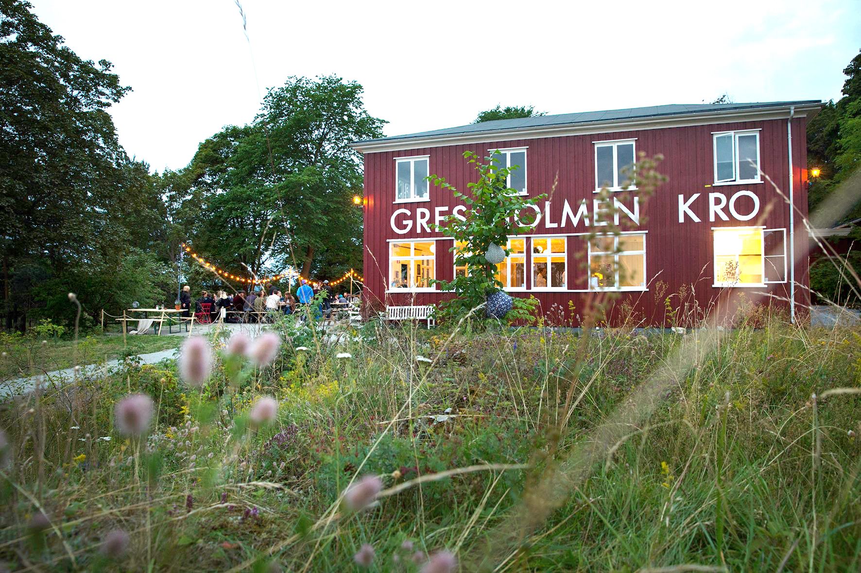 Gressholmen Kro eksteriør, med uteservering, omgitt av skog.