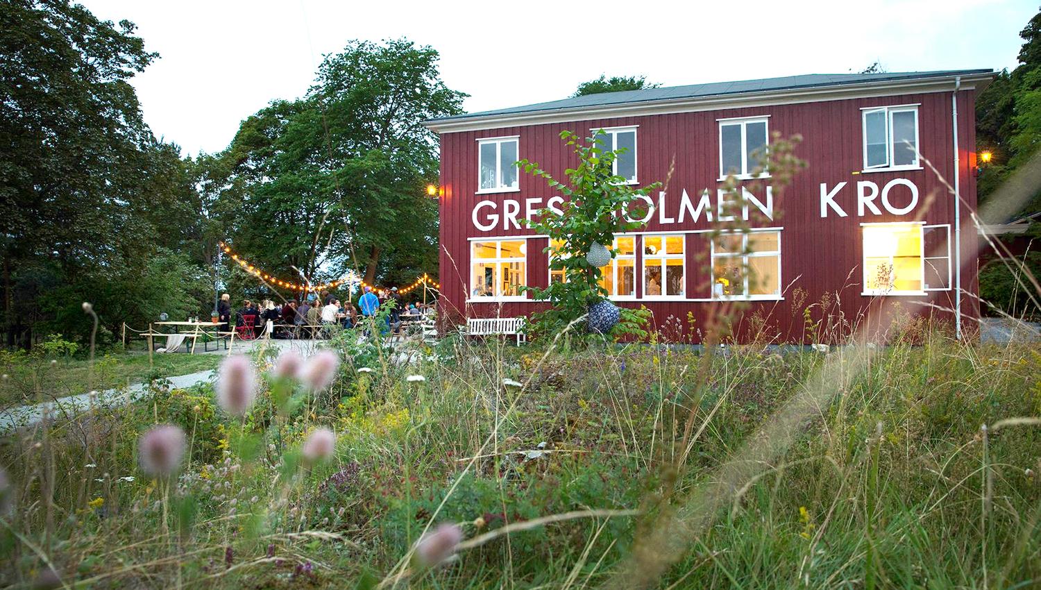 Gressholmen Kro eksteriør, med uteservering, omgitt av skog.