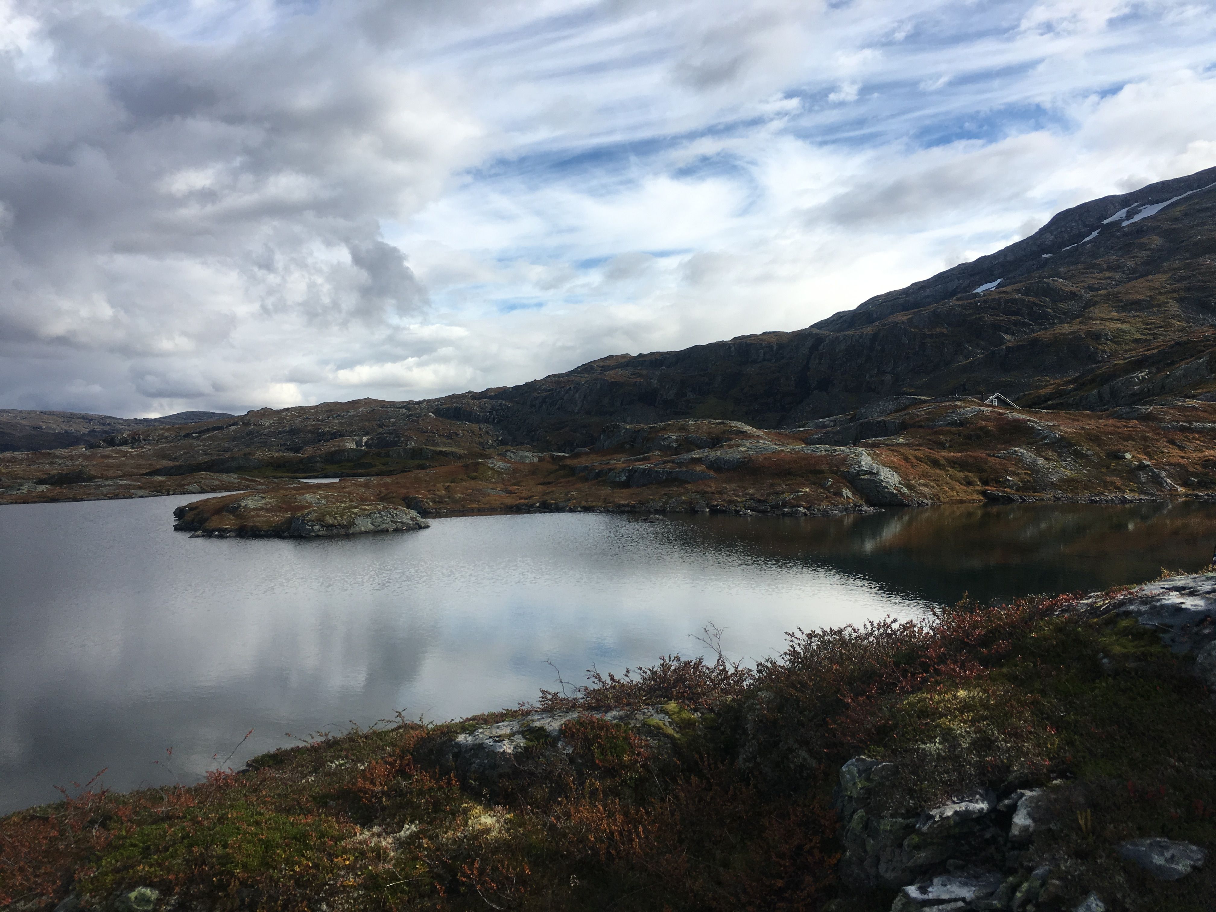 Calm mountain lake surrounded by rolling rocky terrain on Hardangervidda.