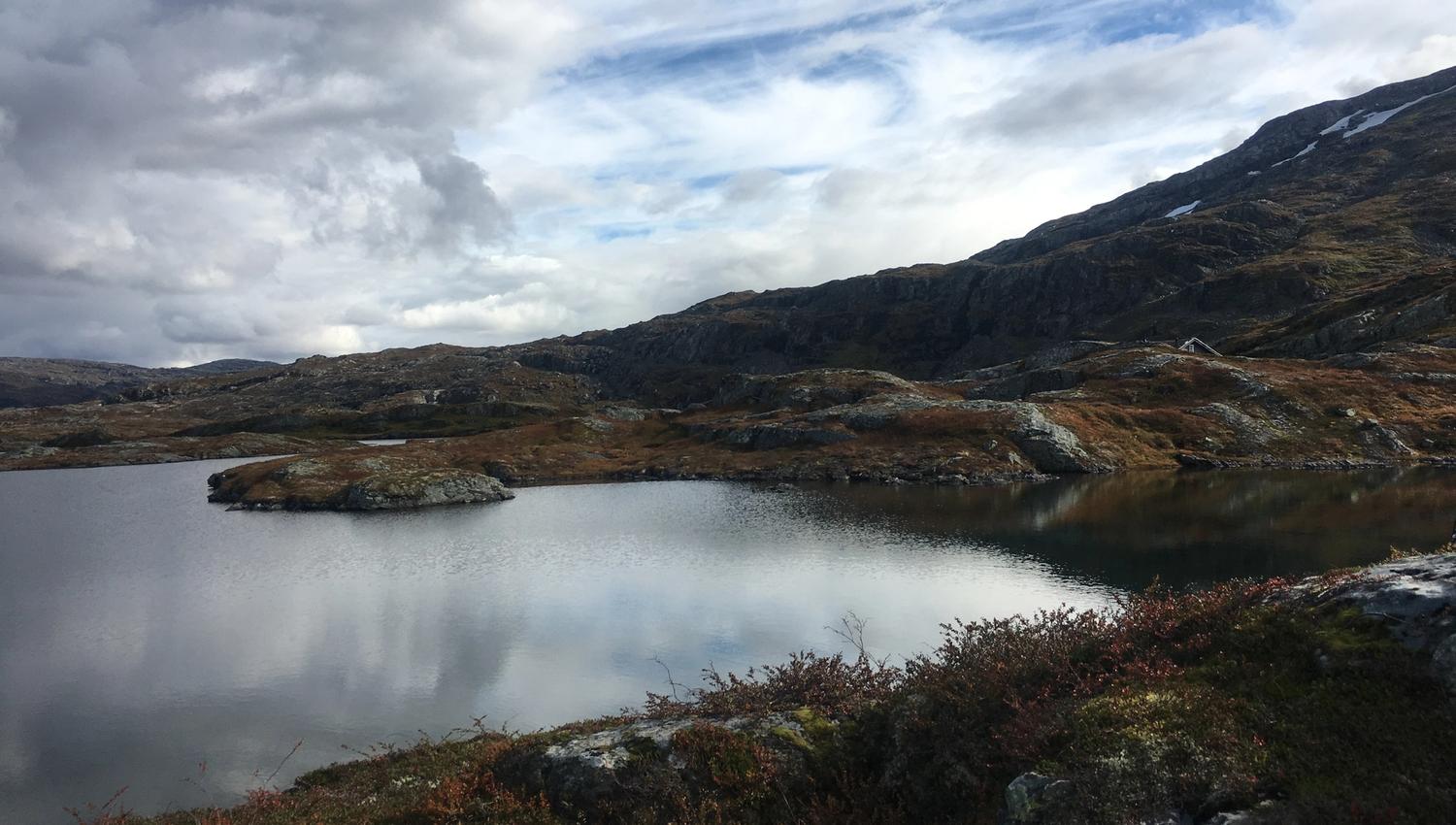 Calm mountain lake surrounded by rolling rocky terrain on Hardangervidda.