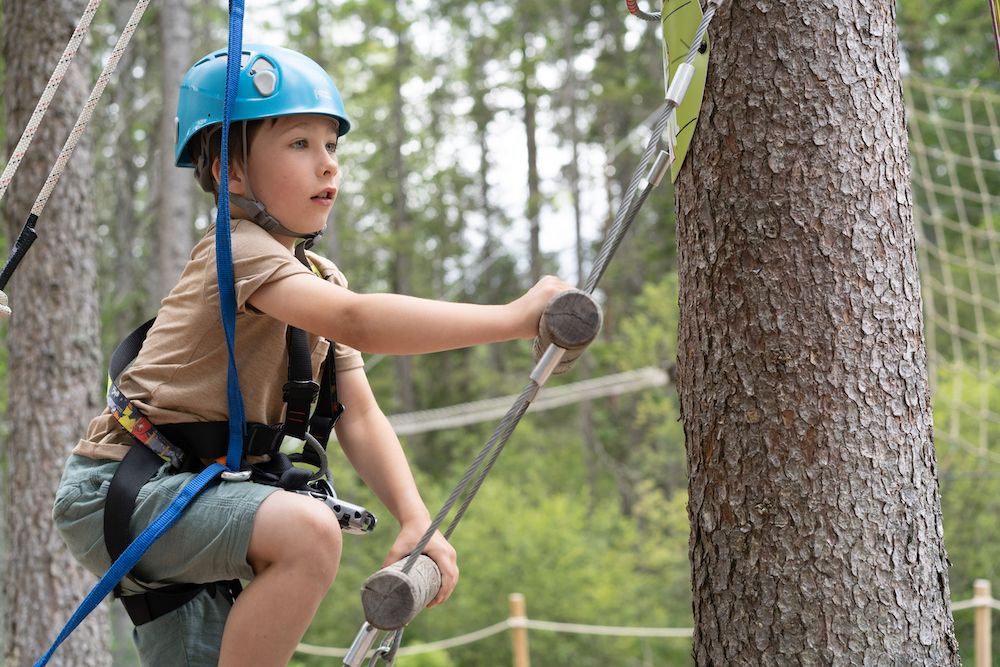 boy walks up a ladder in the climbing park High and Low in Bø in Telemark 