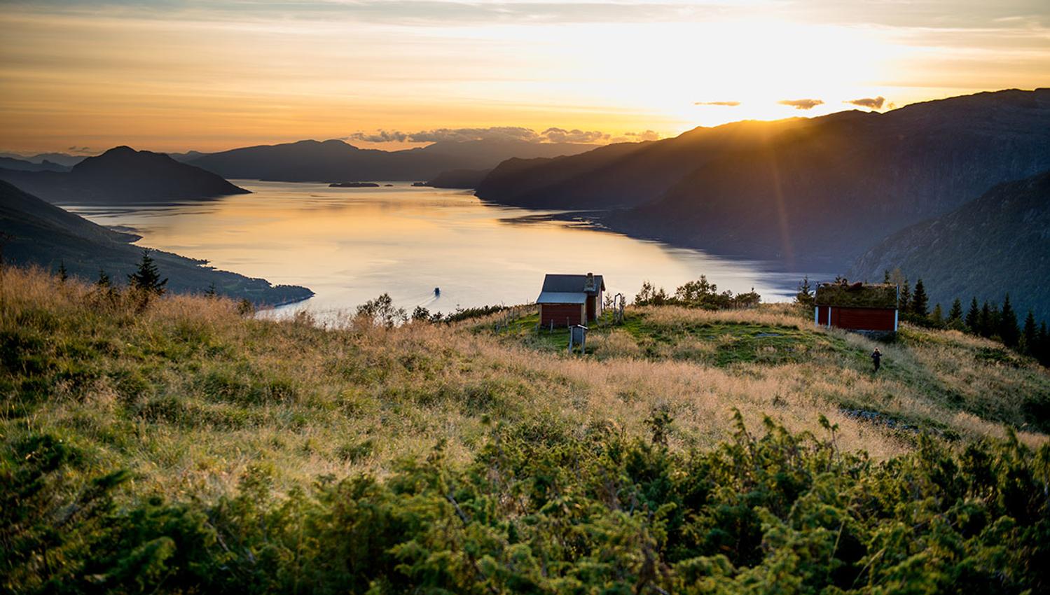 Solnedgang over Hardangerfjorden, med idylliske hytter og fjordutsikt.