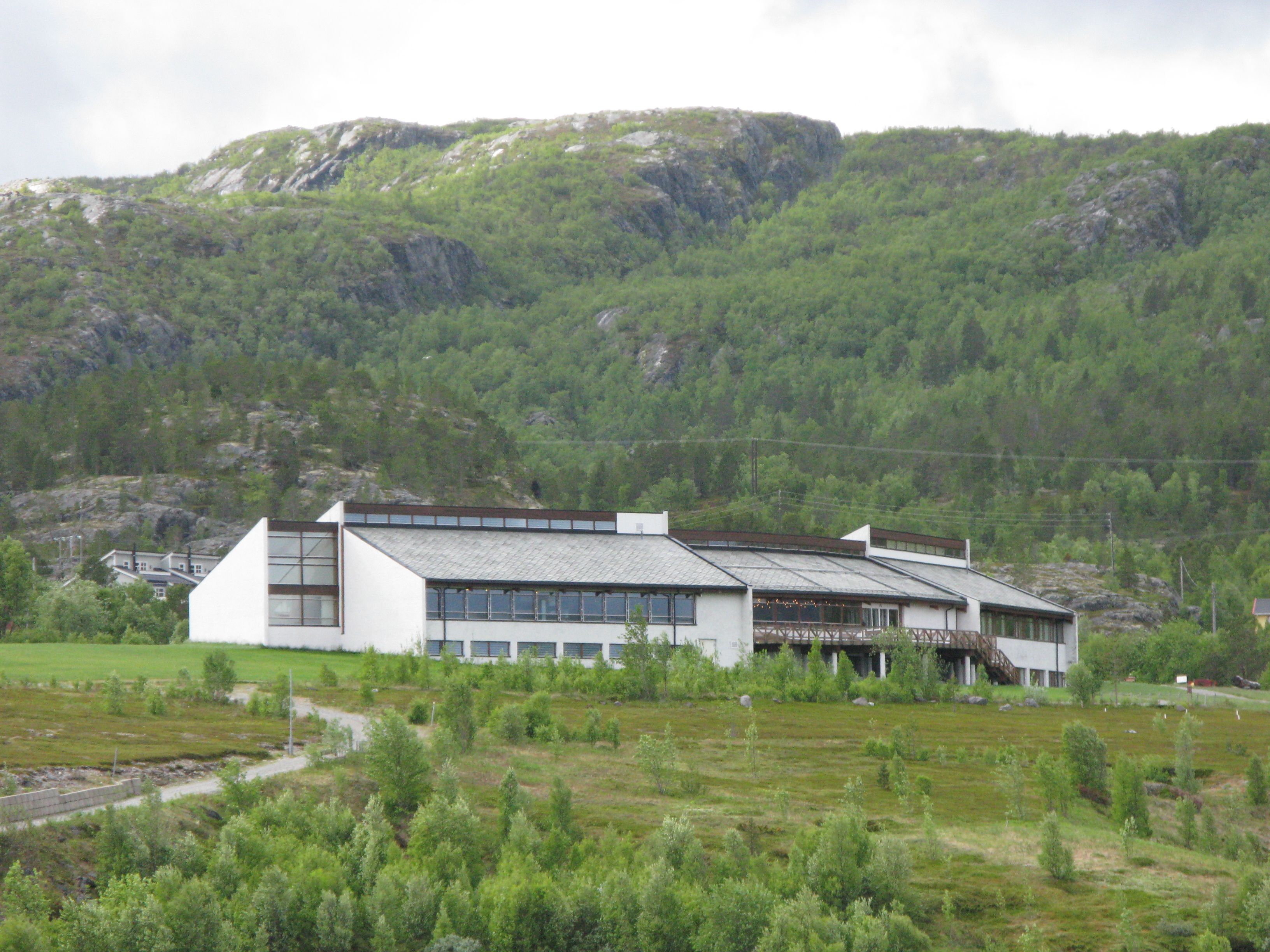 Dieses beeindruckende moderne Gebäude fügt sich harmonisch in die natürliche Umgebung ein. Umgeben von sanften Hügeln und üppigem Grün, ist es ein idealer Ort für Erholung und Abenteuer in der Natur. Genießen Sie die atemberaubende Aussicht!