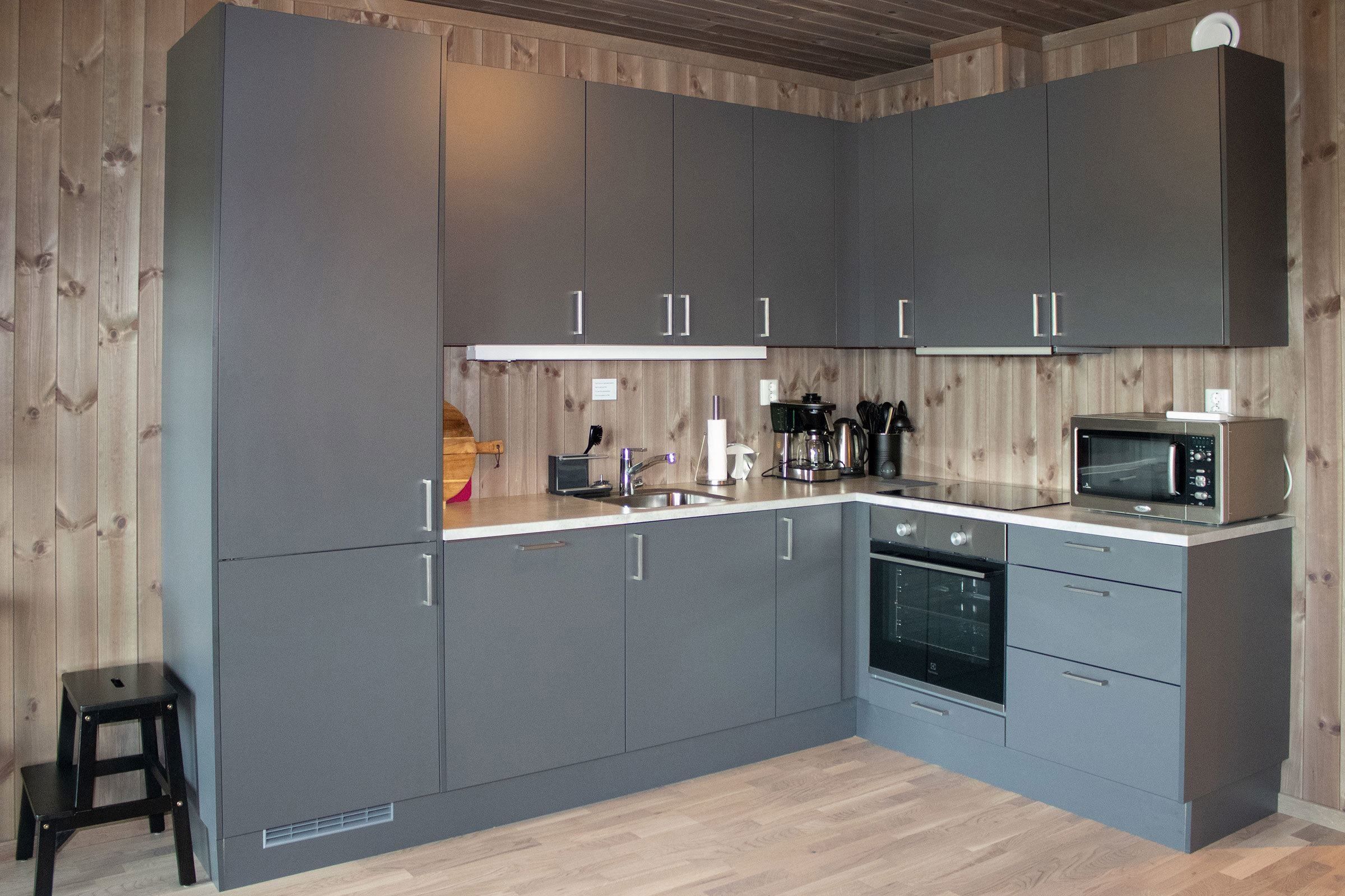 A kitchen with grey cabinets and wooden floors.
