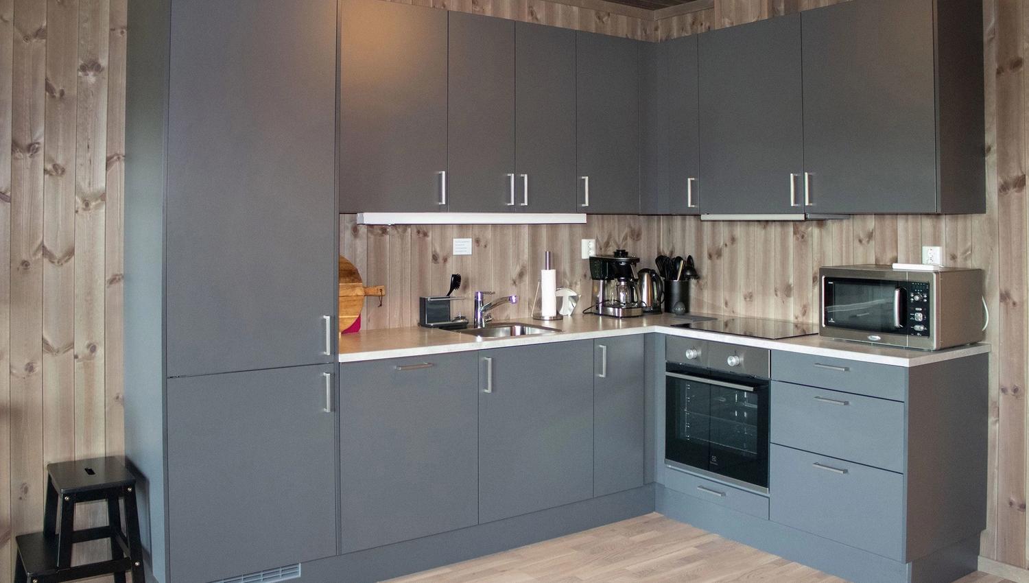 A kitchen with grey cabinets and wooden floors.