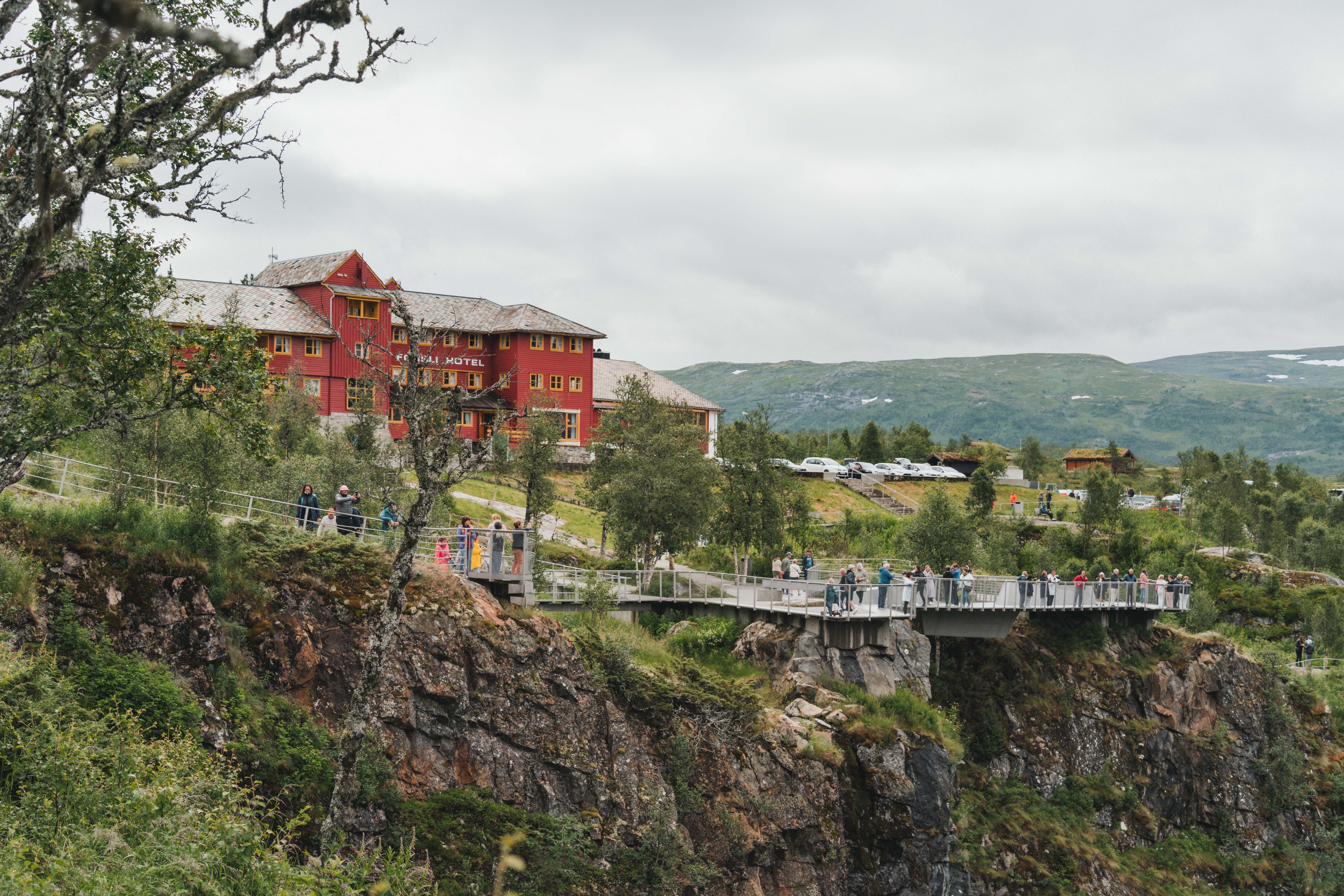 Fossli hotell med utsiktsplattformene og mye folk i forgrunnen.