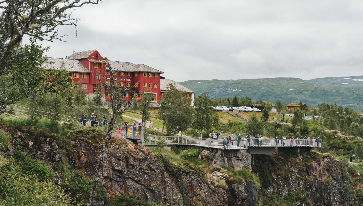Fossli hotell med utsiktsplattformene og mye folk i forgrunnen.