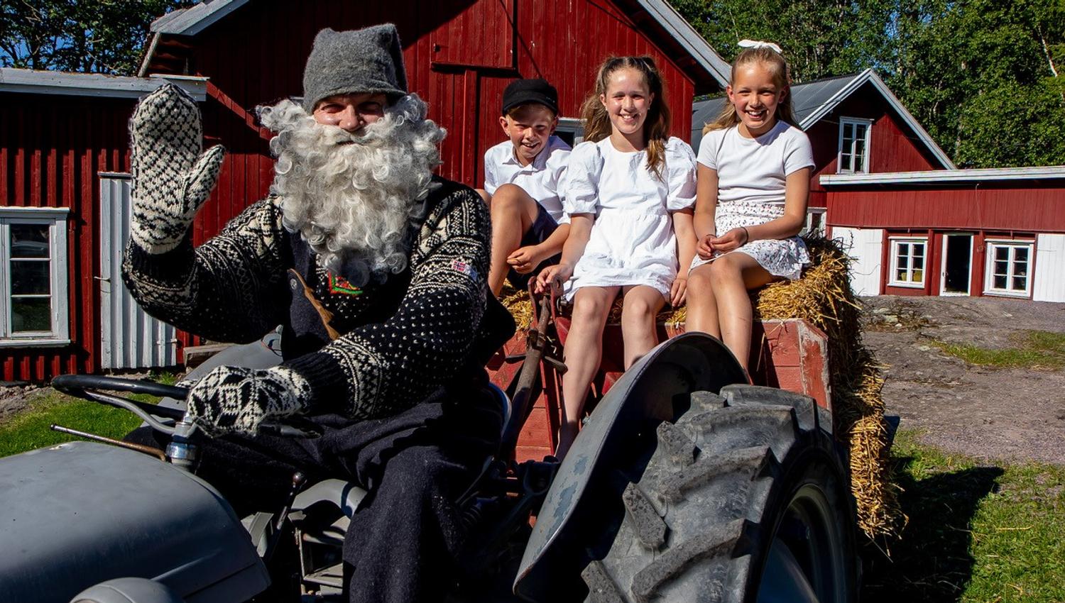 Barn Santa drives a tractor with children sitting in the hay.