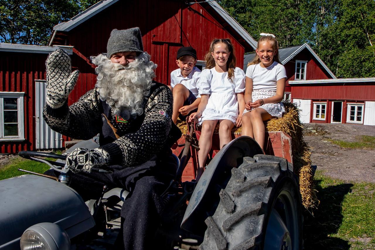 Barn Santa drives a tractor with children sitting in the hay.