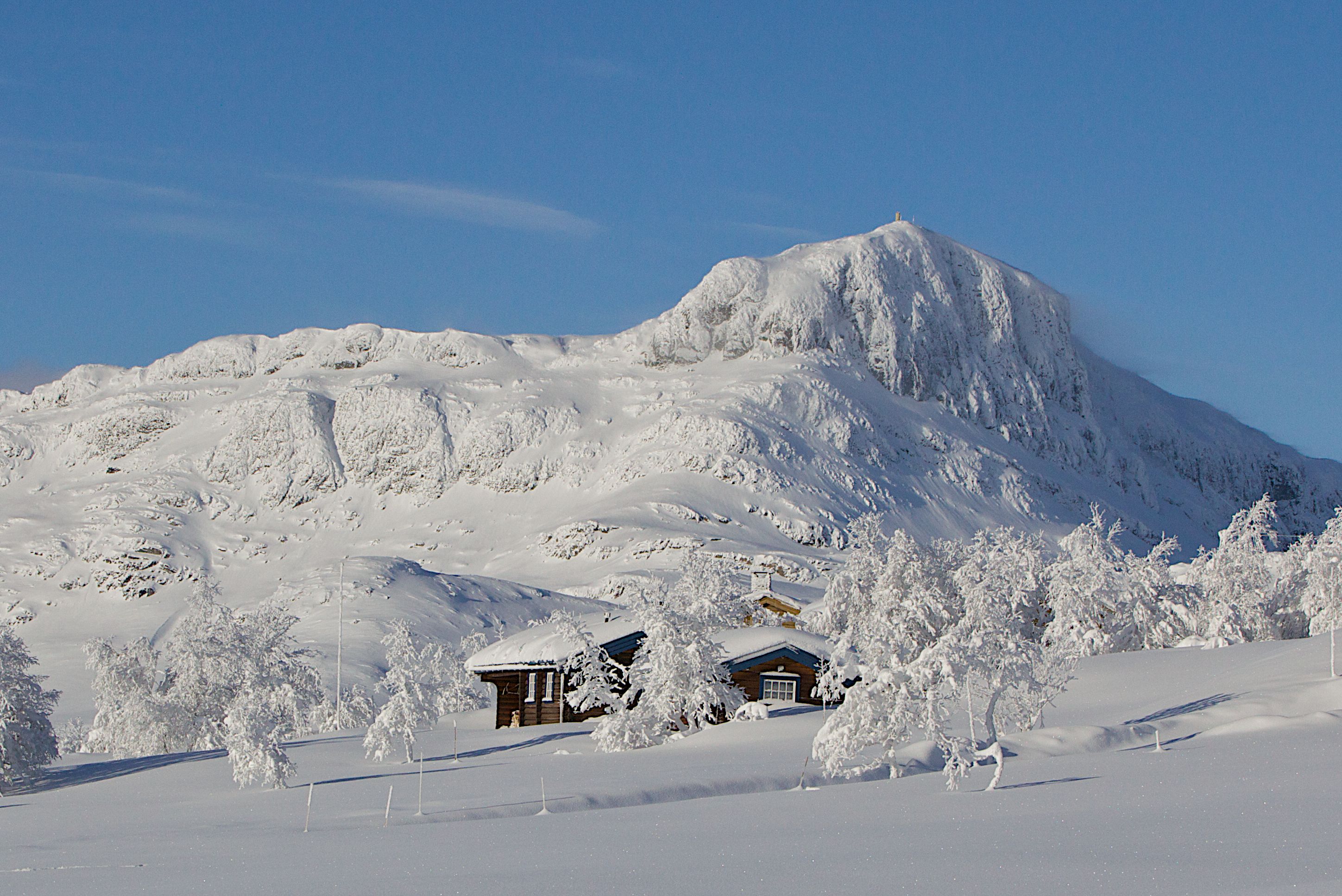 Hytte med det vinterkledde fjellet Bitihorn i bakgrunnen.