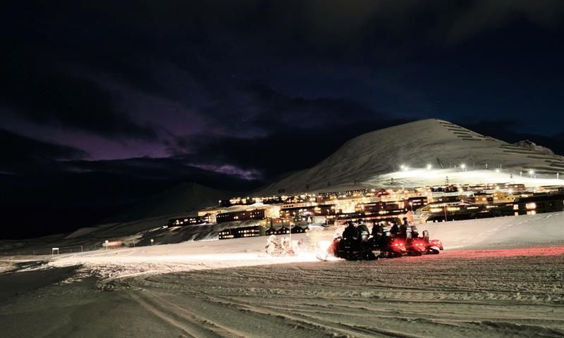 Snowmobiles with Longyearbyen in the background