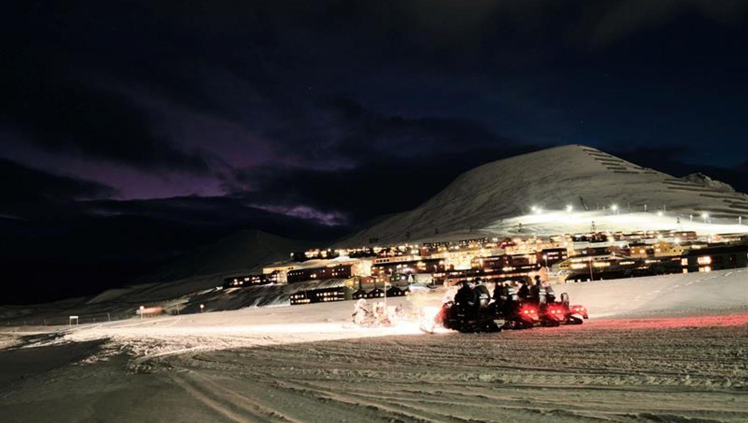 Snowmobiles with Longyearbyen in the background