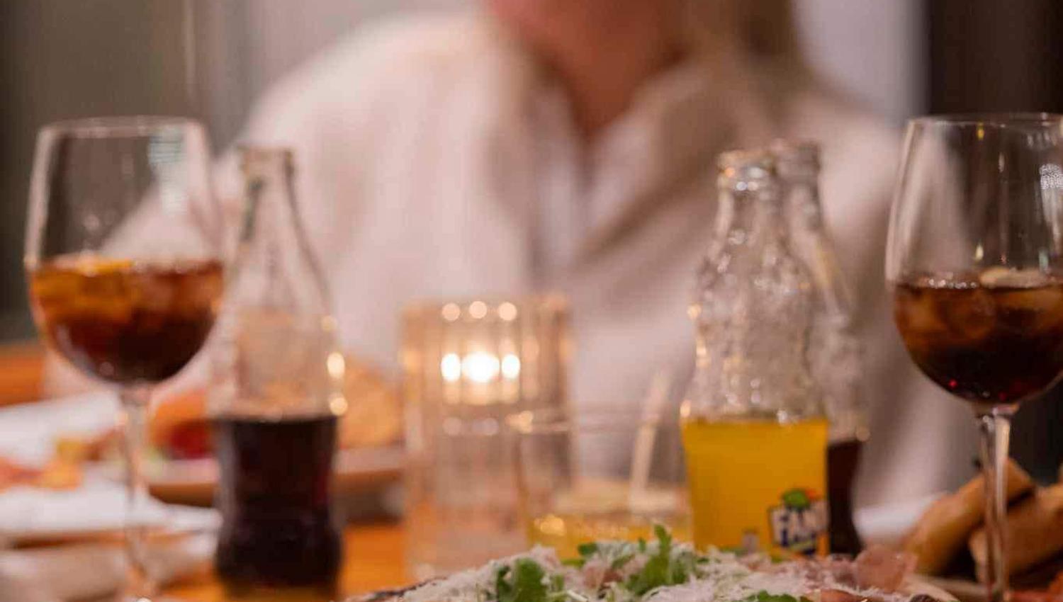 Pizza fra SMOI i fokus og i bakgrunnen kan man se en smilende gjest