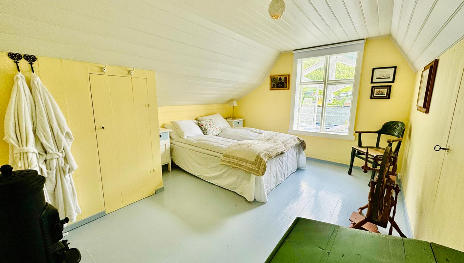 Det gule rommet på Kramsjø Gjestgiveri – varmt og innbydande med utsikt mot fjorden og grøne åsar.