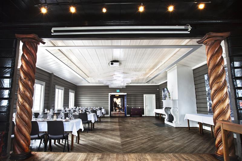 Restaurant interior. Fireplace, tables set for dining with white tablecloths and chairs.
