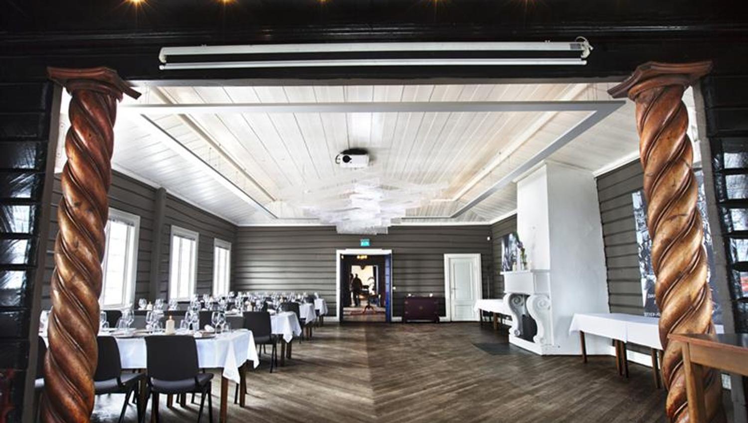 Restaurant interior. Fireplace, tables set for dining with white tablecloths and chairs.